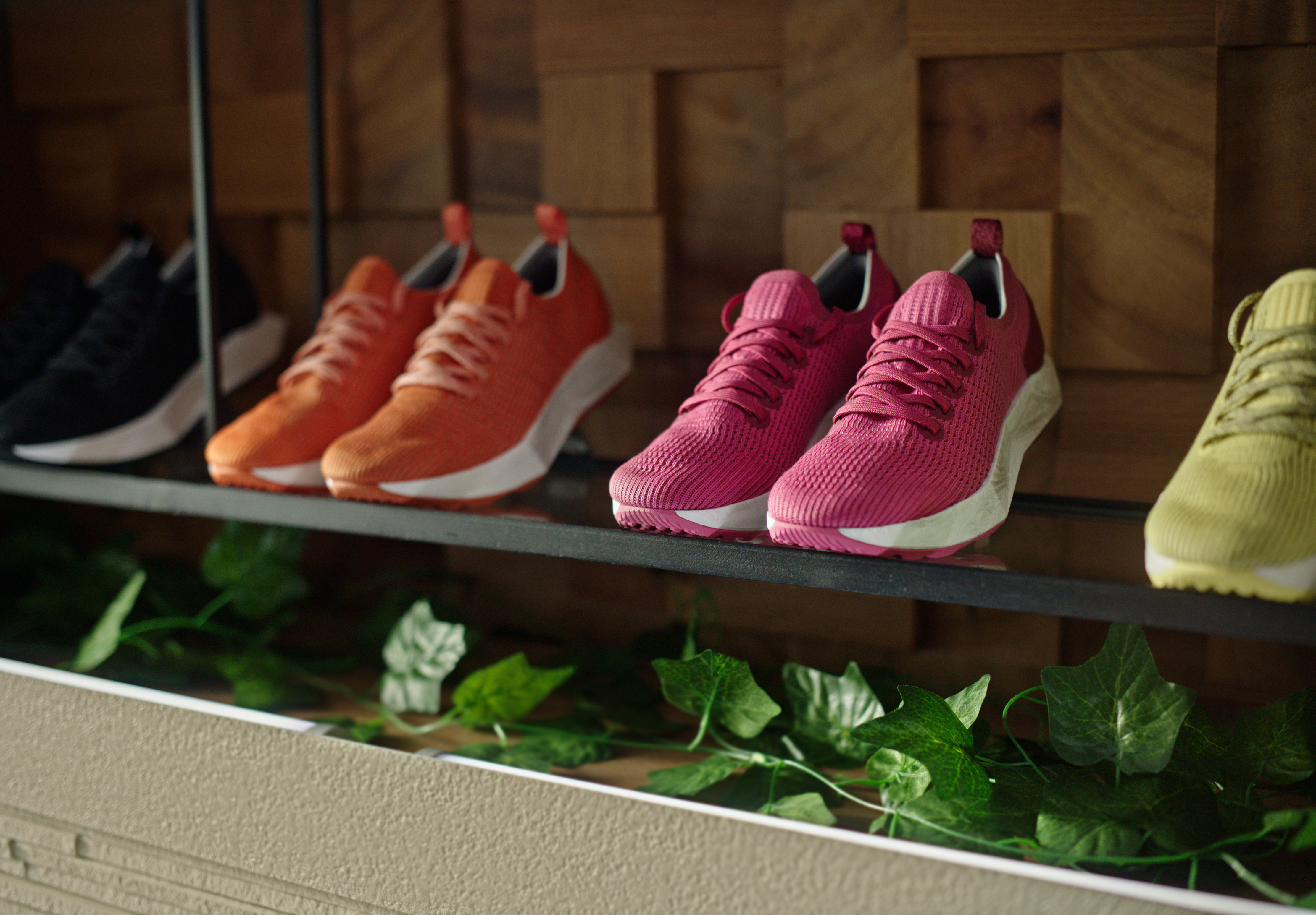 The Allbirds Tree Flyer running shoe in the limited-edition Lux Pink colorway, displayed on a shelf alongside the orange and chartreuse colorways.