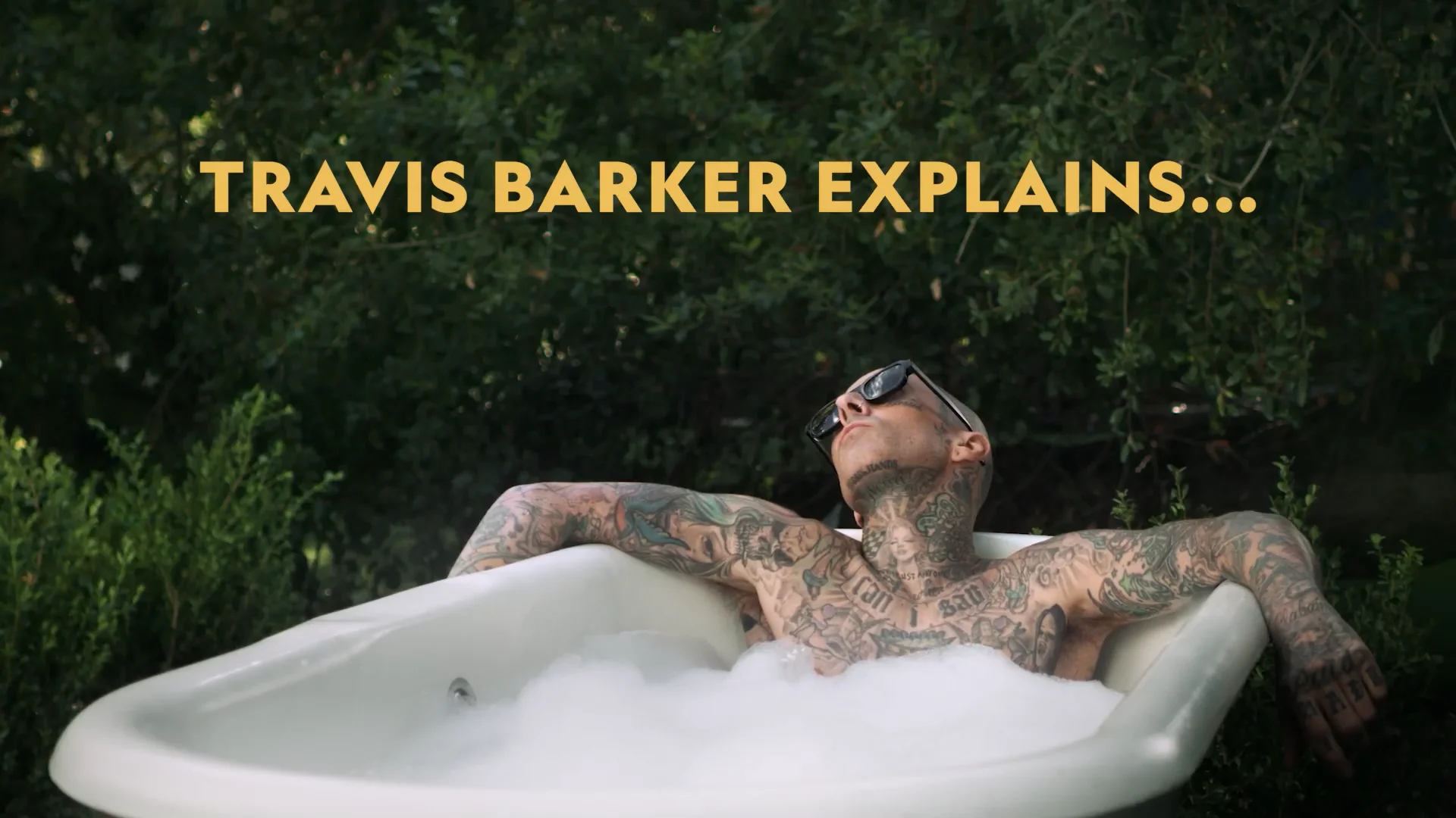 Travis Barker sitting in a bubble bath, holding up a pair of Allbirds Wool Pipers, explaining the brand's Sustainable Public Equity Offering on the day Allbirds went public on the Nasdaq.